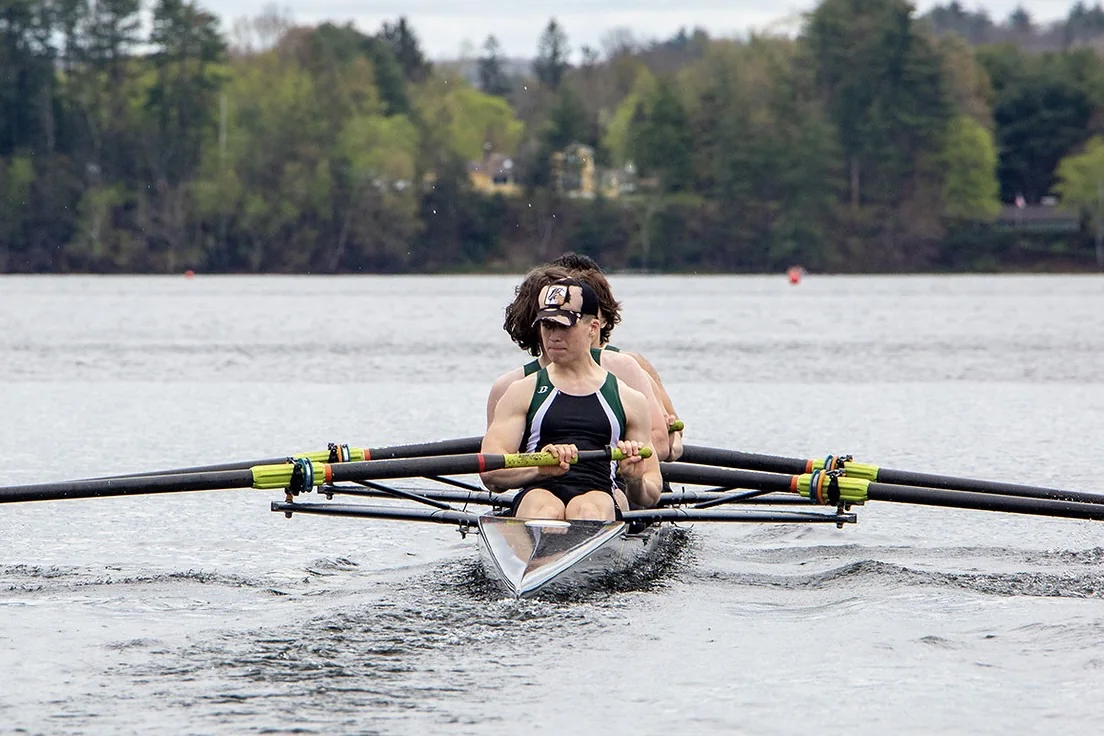 Hudson Murray mid-stroke in a racing shell on open water.